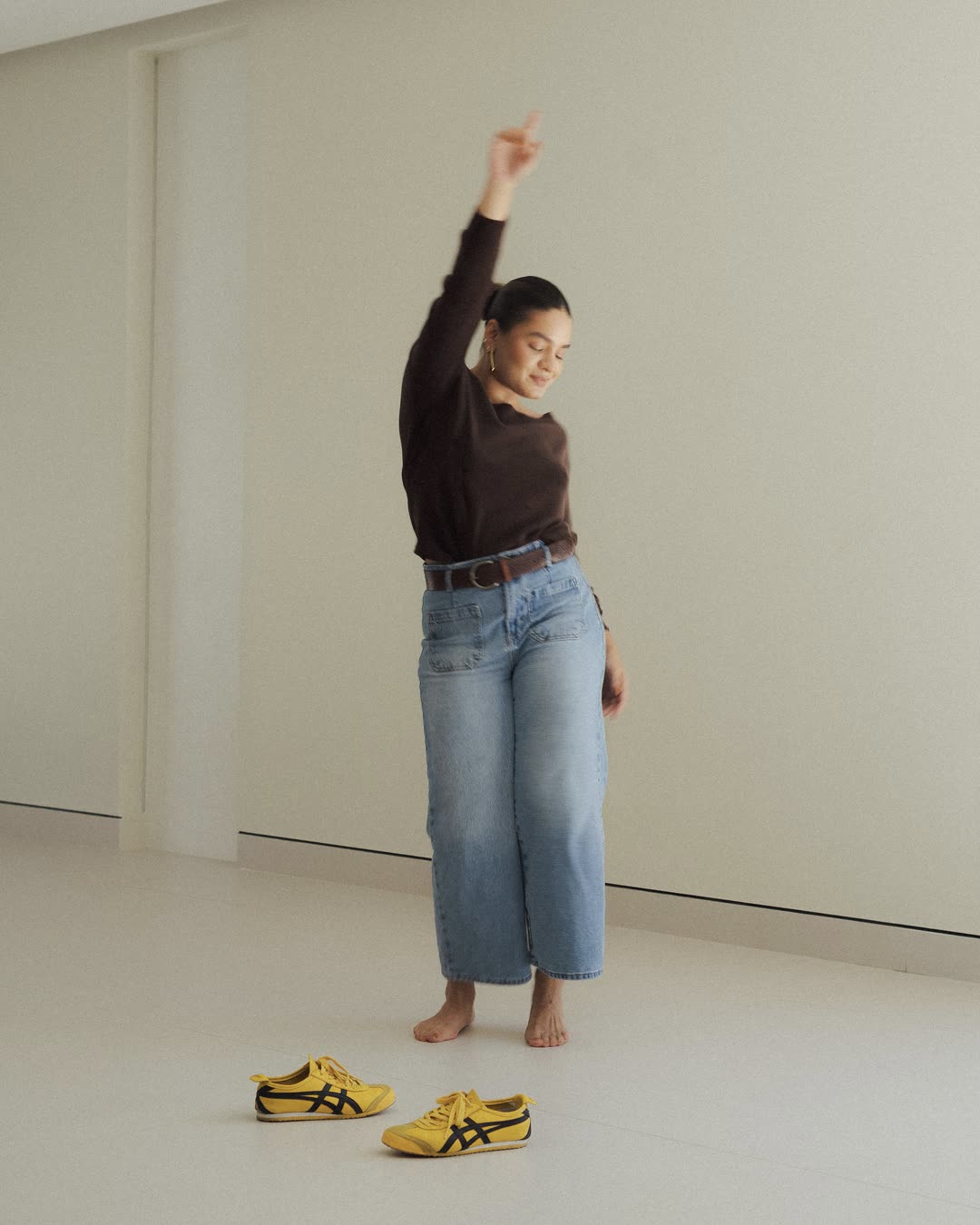 Mafer González de cuerpo entero, con jean y zapatos amarillos, brazo en alto