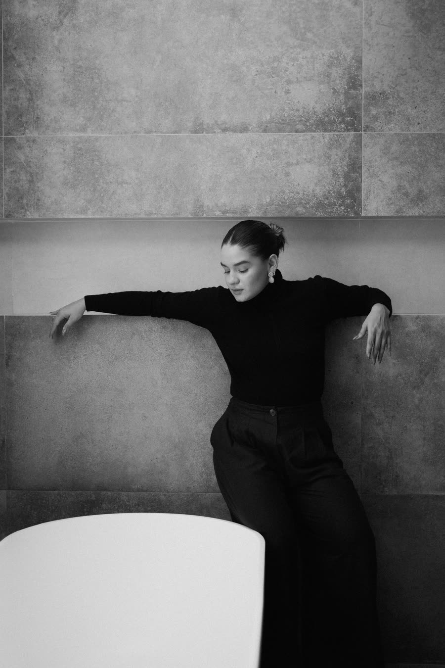 Retrato en blanco y negro, Mafer González apoyada en una pared de piedra junto a una bañera