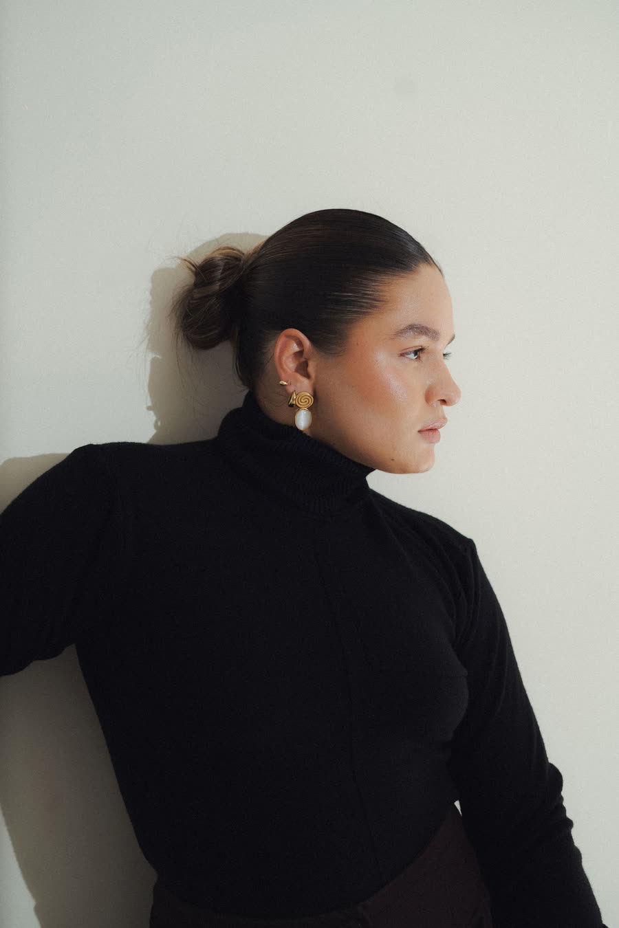 Mafer González de perfil, apoyada en una pared clara