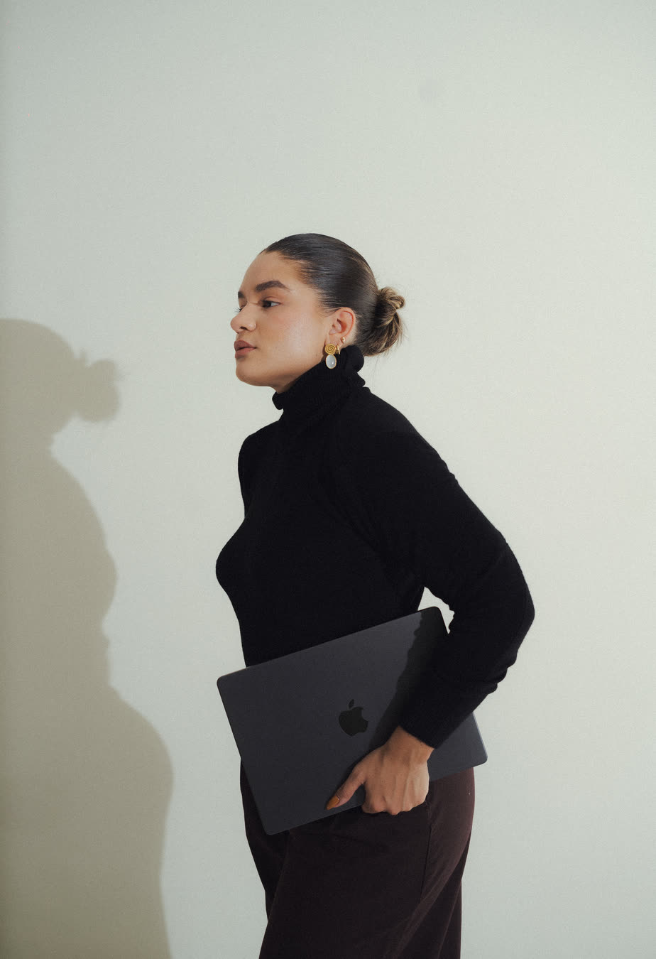 Mafer González de perfil, con una laptop bajo el brazo