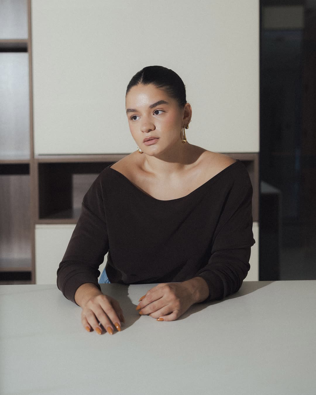 Mafer González sentada a una mesa blanca, mirando a cámara